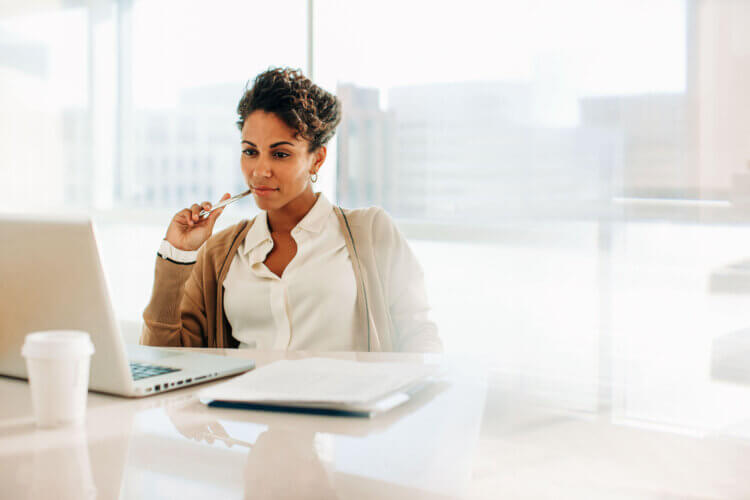 A photo of someone working at a desk looking at a computer reading about FDIC insurance and trust accounts