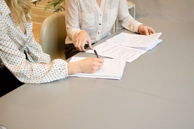 Two people sitting at a table reviewing contracts Two people sitting at a table reviewing contracts