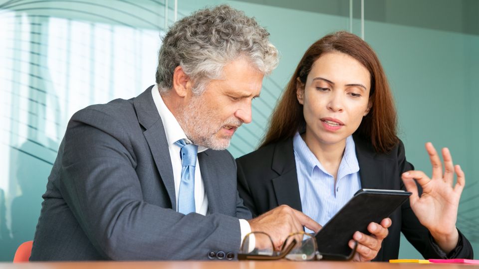 Two people looking at a tablet and having a conversation